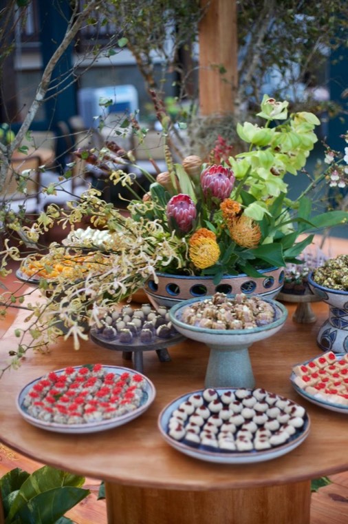 Arranjo floral tropical com proteas e mesa de doces autorais