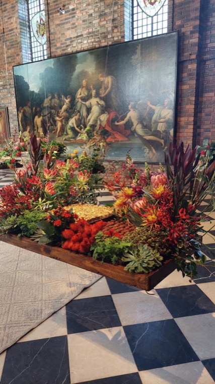 Instalação floral vermelha cenográfica em salão clássico